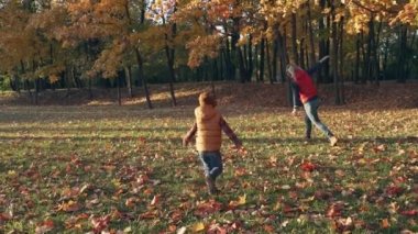 Ağır çekim. Mutlu anne ve oğlu Sonbahar Park sarı yaprakları ile oynamak.
