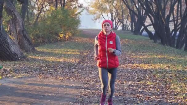 Correr por la mañana de una joven en un parque de la ciudad en una densa niebla. Estilo de vida saludable en cualquier concepto del tiempo — Vídeos de Stock