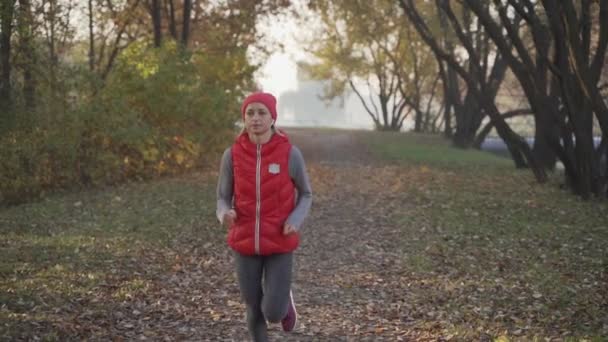 Ochtend joggen van een jonge vrouw in een stadspark in een dichte mist. Sunrise. Gezonde levensstijl in een weer-concept — Stockvideo