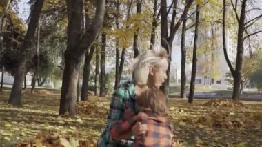 Anne ve oğlu Sonbahar Park eğlenmek ve sarı yapraklar bir yığın yalan. Anne sarılma çocuk