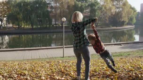 Jonge moeder met plezier met haar zoon in herfst park op zonnige dag — Stockvideo