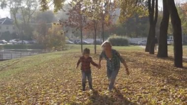 Sonbahar düşen yapraklar çalışan kadın ve 5 yıllık çocuk. Anne ve oğlu sonbahar keyfini çıkarın