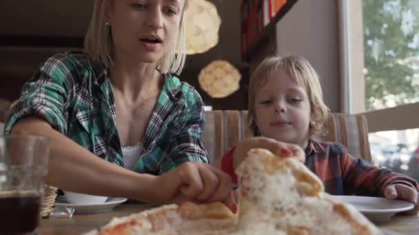 Mujer y niño de 5 años comiendo pizza en la cafetería — Vídeos de Stock