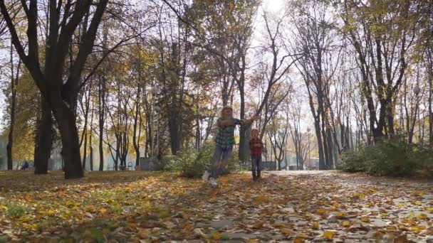 Jonge moeder met plezier met haar zoon in herfst park op zonnige dag — Stockvideo