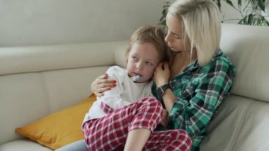 Annesi hasta çocuğunu arka plan, sıcaklığı ölçme. Yüksek ateşle evde kanepe yalan hasta çocuk