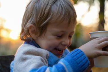 Çocuk Kupası düşen yapraklar arka plan üzerinde elinde tutar. Sonbahar ruh hali güzel bir gün. Natürmort altın sonbaharda. Parlak sonbahar resim.