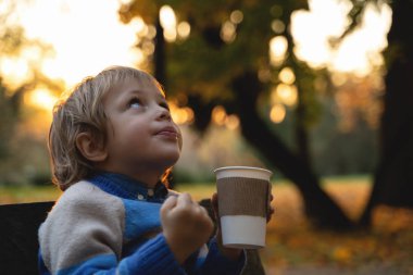 Çocuk Kupası düşen yapraklar arka plan üzerinde elinde tutar. Sonbahar ruh hali güzel bir gün. Natürmort altın sonbaharda. Parlak sonbahar resim.