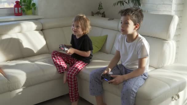 Δύο παιδιά συναισθηματικά παίζοντας βιντεοπαιχνίδια στο σπίτι στο ηλιόλουστο πρωί — Αρχείο Βίντεο