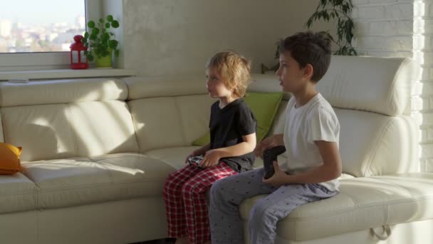 Δύο παιδιά συναισθηματικά παίζοντας βιντεοπαιχνίδια στο σπίτι στο ηλιόλουστο πρωί — Αρχείο Βίντεο