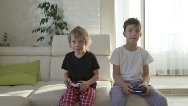 Двоє дітей емоційно грають відеоігри вдома в сонячний ранок — стокове відео
