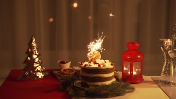 Mujer joven encendiendo un Sparkler en el pastel por la noche en tiempo de Navidad — Vídeo de stock