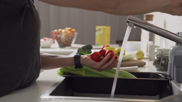 Woman washes tomatoes, vegetables in the kitchen. Close-up. 4k footage. — Stock Video