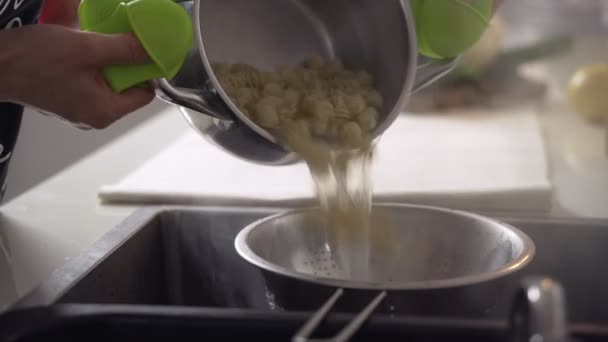 Pasta bollente. Scolare l'acqua dei maccheroni attraverso un colino nel lavandino — Video Stock