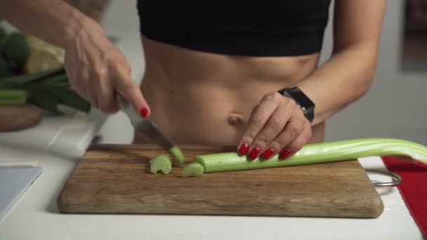 Спортивная женщина режет сельдерей на доске для приготовления домашнего овощного салата — стоковое видео