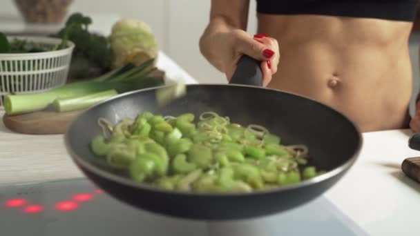 Close-up-Kochen gebratene grüne Zwiebeln und Sellerie wirft sie in der heißen Pfanne. Zeitlupe — Stockvideo