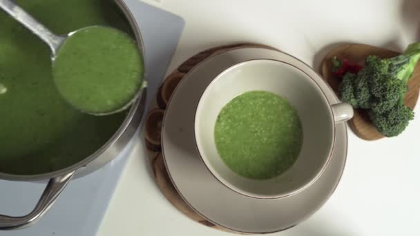 Питание, кулинарное и здоровое питание концепция - крупным планом овощной зеленый суп романско крем в миске с рукколой и ложкой на кухонном столе — стоковое видео