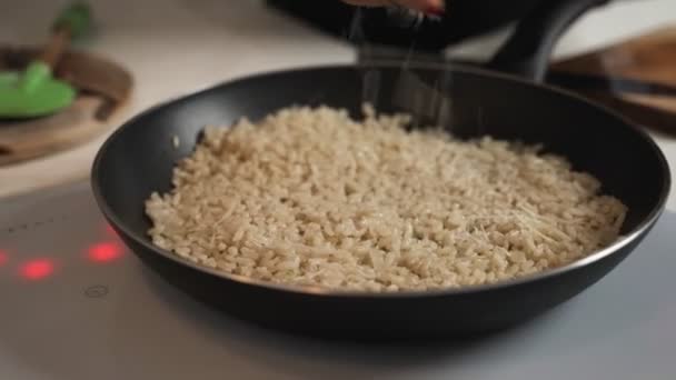 Afeitar trozos de queso parmesano en risotto caliente en una sartén grande de acero inoxidable, cerrar el video — Vídeo de stock