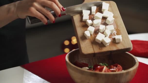 El tiro de la mitad de la sección de las manos de la hembra irreconocible poner cubos de queso feta en un tazón con verduras — Vídeos de Stock