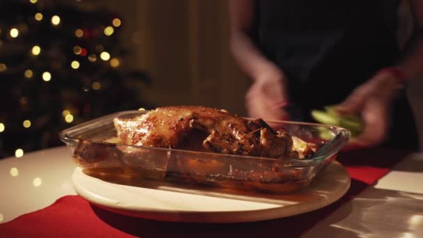 Womans hands pouring honey and mustard on roasted goose. Goose roasted with apples and oranges in oven. Christmas tree at background — Stock Video