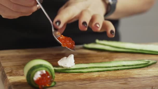 Kvinnliga händer att göra mellanmål rulle kaviar ost och gurka — Stockvideo