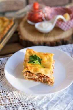 Klasik hommade lazanya dantel masa örtüsü ile ahşap tabloda bolognese soslu