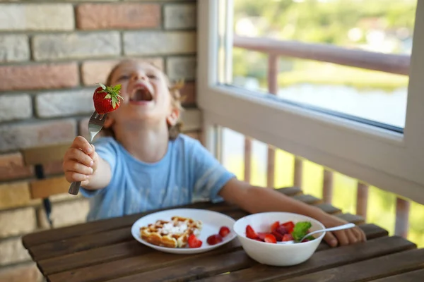 Happy 5 year old caucasian boy eat for Breakfast Viennese waffles with ice cream and strawberries — Stock Photo, Image