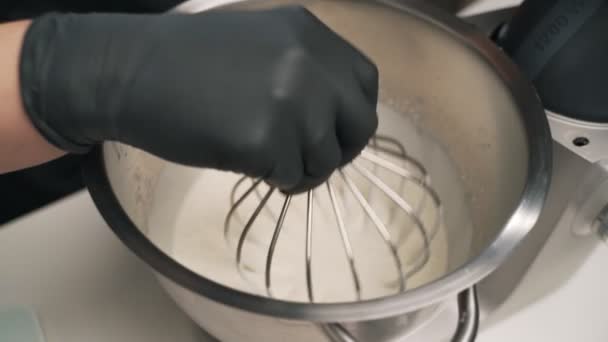 Konditorin in schwarzer Uniform bereitet Sahne für Schokoladenmoussekuchen zu. Bühne Kochen Moussekuchen — Stockvideo