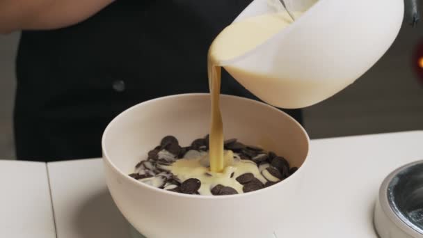 Mujer confitera en uniforme negro preparar crema para pastel de mousse de chocolate. Tarta de mousse de cocina etapa — Vídeos de Stock