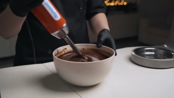 Mujer confitera en uniforme negro preparar crema para pastel de mousse de chocolate. Tarta de mousse de cocina etapa — Vídeo de stock