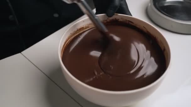 O confeiteiro de mulher no uniforme preto prepara a nata para o bolo de musse de chocolate. Bolo de mousse de cozinha de palco — Vídeo de Stock