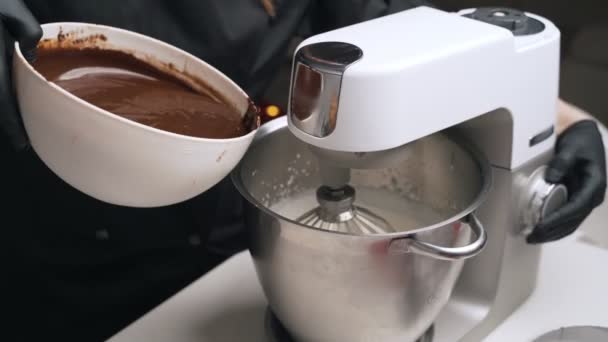 Mujer confitera en uniforme negro preparar crema para pastel de mousse de chocolate. Tarta de mousse de cocina etapa — Vídeos de Stock