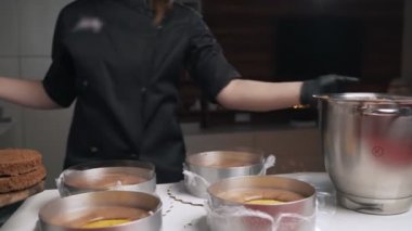 Siyah üniformalı kadın pudra krem çikolata mousse kek için hazırlayın. Sahne pişirme mousse kek
