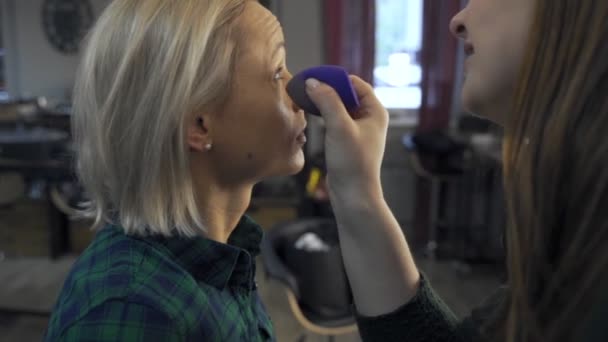 Maquillaje profesional artista en el trabajo cepillo mano primer plano belleza industria de la moda cosméticos detrás del escenario maquillaje profesional vista lateral macro hermosa iluminación natural en estudio con ventanas — Vídeo de stock