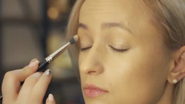 Profesyonel makyaj sanatçısı, iş fırça el closeup - güzellik moda endüstrisi kozmetik sahne arkasında profesyonel makyaj - yan makro görünümü güzel doğal ışık Studio windows ile