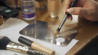Profesyonel makyaj sanatçısı, iş fırça el closeup - güzellik moda endüstrisi kozmetik sahne arkasında profesyonel makyaj - yan makro görünümü güzel doğal ışık Studio windows ile