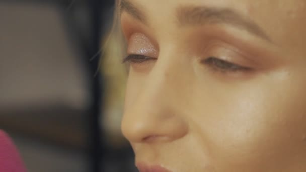 Artista de maquiagem profissional fazendo maquiagem ocular para jovem modelo — Vídeo de Stock
