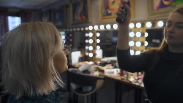 Professional make-up artist at work brush hand closeup - beauty fashion industry cosmetics backstage professional makeup - side view macro beautiful natural lighting in studio with windows — Stock Video