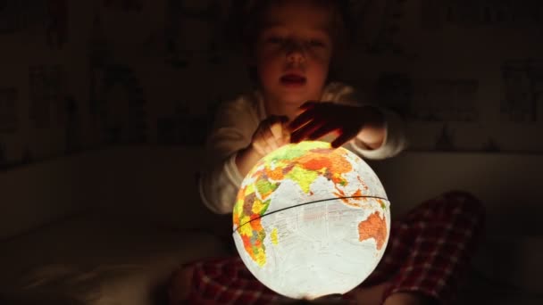 Két fiú ült az ágyban éjjel forgó a globe és a utazótáska álmok. — Stock videók