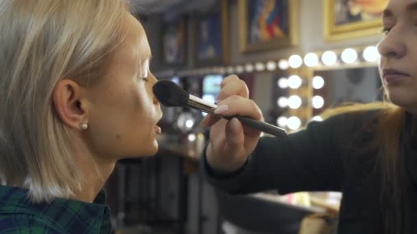 Maquillaje profesional artista en el trabajo cepillo mano primer plano belleza industria de la moda cosméticos detrás del escenario maquillaje profesional vista lateral macro hermosa iluminación natural en estudio con ventanas — Vídeo de stock