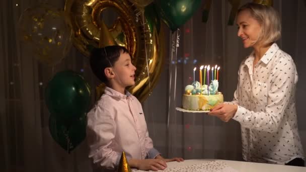 Порожнеча милого веселого хлопчика, що дме свічки на торт і плескає руками під час вечірки на день народження вдома . — стокове відео