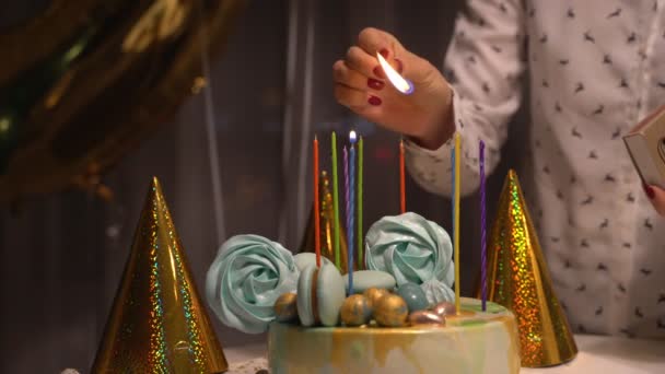 Крупним планом жіночі руки освітлюють свічки на смачний торт на день народження. Підготовка до вечірки . — стокове відео