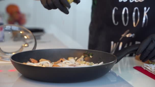 Gebratene Tintenfischringe mit Kräutern und Zwiebeln in der Pfanne. — Stockvideo