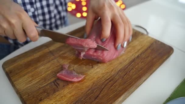 Diapositiva de una joven hembra cortando carne cruda con un cuchillo en un tablero de plástico, imágenes de 4k . — Vídeo de stock