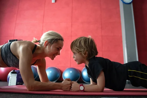 Anne ve oğlu tahta poz, phalankasana, fitness Center'da yoga seansı sırasında ayakta.