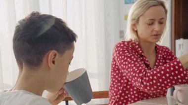 Bir sevimli sevimli beyaz çocuk sarı saçlı genç annesiyle yanında çerez yiyor.