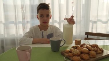 İki erkek modern mutfakta kahvaltı. Çocuk süt ile kurabiye ye. Beyaz masa mutfak. Anne ve iki oğlu kahvaltı edelim. Süt ile tanımlama.