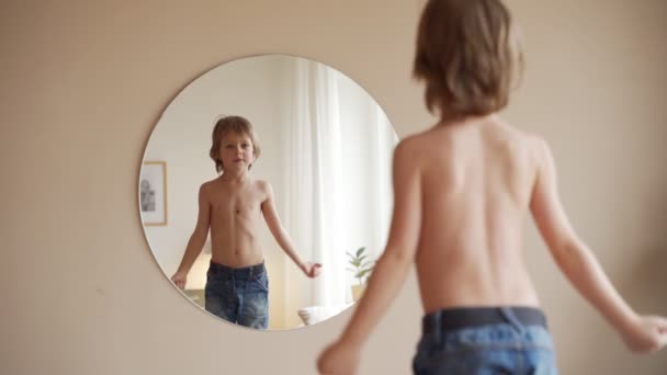 Confident kid looking at his muscles in mirror imagining that he is super hero — Stock Video