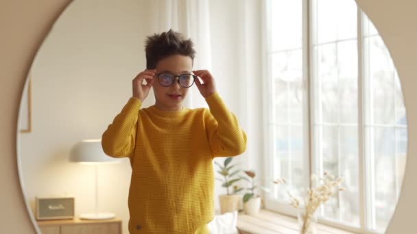 Teen boy is choosing new eyeglasses in front of a mirror — Stock Video