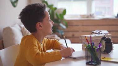 Çocuk okul ödev, bir tükenmez kalem bir not defterinde yazıyor.