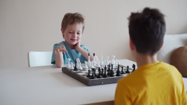 Deux garçons jouant aux échecs dans une pièce lumineuse. Deux frères jouant aux échecs . — Video